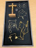 All items in the lot including crucifix, rosary, necklace, ring, and earrings displayed in a black tray.