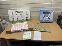 Photo of Wii Fit box with balance board, game manual, and Sports Pack box containing multiple white accessory attachments.