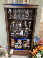 Front view of antique wooden shelf filled with glassware, ceramics, and other decorative items to illustrate shelf size and design.