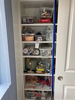 Full shelving unit with multiple plastic bins and containers holding arts and crafts items including stamps, pipe cleaners, felt, embroidery hoops, paints, and fabric.
