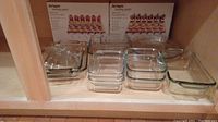 Photo of multiple clear Pyrex glass baking pans including square, rectangular, and round dishes with two Pier 1 tasting party kits in original packaging at the back.