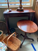 Two wooden tables shown: a rectangular side table with drawer and a round pedestal tilt-top table with tripod base. Both with visible surface scratches and scuffs.