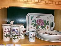 Shelf view with tall mugs, footed mug, carafe, plate, bowl and tray