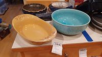 Oval beige bowl and round blue mixing bowl shown on table with pie pan partially visible