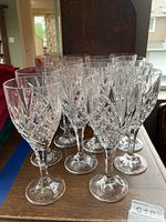 Front view of fourteen clear crystal goblets arranged closely, showcasing the cut glass diamond and fan patterns around the bowl and stems.