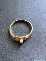 Close-up top view of the 10K gold ring showing diamond and detailed floral design on band.