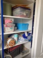 Photo of shelving unit with plastic bins containing sewing supplies including stuffing, ribbons, and other materials.