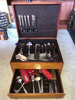 Overview of the wooden storage box with silverplated flatware inside, showing upper and lower drawers with various utensils.