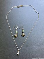 Full view of sterling silver necklace and earrings laid flat on black background