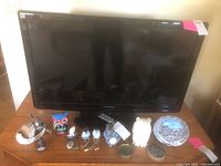 Dynex 38-inch TV with assorted decorative figurines placed in front of it on a wooden surface.