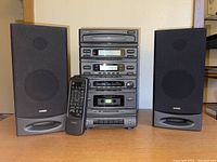 Front view of Jensen stereo stack including cassette player, CD changer, tuner, control modules, two bookshelf speakers, and remote control placed in front.
