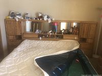 Full view of the king size oak headboard with a mattress leaning against it, showing the storage cabinets and mirror.