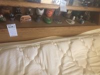 Miniature owl figurines displayed on a wooden shelf, showing a variety of sizes, colors and styles.