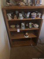 Full view of oak bookshelf filled with various ceramic mugs and decorative items on shelves, showing overall condition and shelf arrangement.