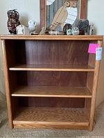 Full front view of the oak bookshelf showing three shelves and wood grain detail.