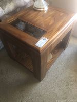 Side view of an oak end table showing glass insert on top and open lower shelf.