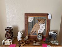 Overall view showing all eleven owl items including framed wooden art, ceramic and wooden figurines, and metal basket with contents.