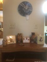 Full view of wooden table surface displaying various owl themed items including figurines, framed art/photo, and a wall clock above them.