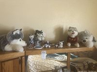 Eight plush husky dog toys of various sizes arranged on top of a wooden dresser with mirror.