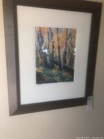 Framed signed print showing an autumnal forest scene with tall trees and colorful leaves.