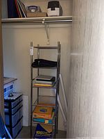 Photo of closet showing metal shelving unit with assorted office supplies and plastic four-drawer drawer unit to left