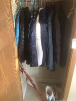 Photo of five womens jackets hanging on hangers in a closet space, sizes medium and large.