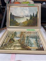 Both vintage landscape oil paintings together showing frontal view of each painting and frames.