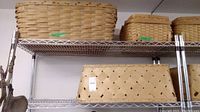 Three vintage wooden woven baskets on a metal wire shelf, featuring rectangular shapes and natural wood tones, one with a handle on top.