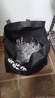 Black bag filled with numerous clear chandelier crystal prisms of various sizes and shapes.
