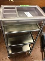 Metal utility cart with plastic tray featuring compartments on top, three metal shelves below, and four wheels.