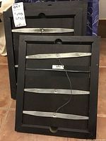 Four black wooden contact print frames stacked, showing backs with metal spring strips and hanging wire