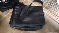 Top front angled view of the Latico black leather crossbody bag showing the flap and strap.