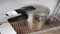 Seb pressure cooker with handle and lid, viewed from side on a wire rack shelf