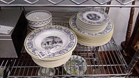Metal shelving unit holding stacks of plates and bowls showing overall assortment