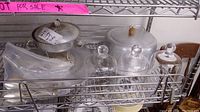 Photo of vintage aluminum chafing dish, glass cloches, cake plate with dome, and flatware on metal shelf