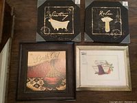 Overview photo showing all four art pieces together. Two canvas art pieces with black backgrounds and gold details, and two framed prints, one black framed 'Bath Oil' print with damage and one gold-toned framed bathroom tub print.