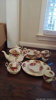 Overall photo showing the tea set pieces including teapot, cups, plates, and sugar bowl arranged on the floor near a window.
