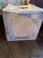 Closed cardboard box showing image of the dinnerware pieces including cups, plates, and saucers arranged on front.