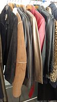 Side view of hanging jackets in various colors including brown, black, red, and leopard print, showing different materials and styles.