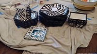 Photo showing the stacked Roscher Zebra patterned dinner plates, salad plates, bowls, and matching cups with handle, all on a cloth.