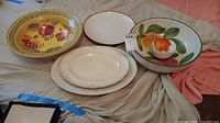 Overview of various ceramic serving bowls and platters with fruit and floral motifs, including the Homer Laughlin platter