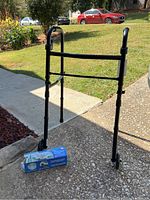 Full view of black folding Equate walker with two front wheels and upright grips, positioned outdoors on pavement.