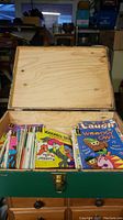 View of open wooden box filled with assorted vintage children’s comics visible inside the box.