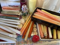 Wide view of assorted candles including tapers, pillar candles and carved multicolor candle
