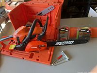 Overview of Echo chainsaw in open case with guide bar, chain and tools