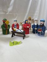 Colorful wooden nativity figurines including Baby Jesus, Mary, Joseph, and three Wise Men around a wooden manger