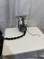 Front and side view of Crosley rotary dial phone with handset on cradle and coiled cord visible.