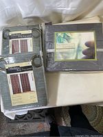 Photo of two packaged Medina Ring Top curtain panels and one packaged bamboo queen size sheet set.
