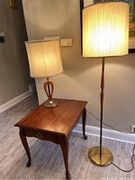 Photo showing solid wood side table with Queen Anne legs, dovetailed drawer, next to two lamps.