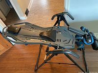 Teeter FitSpine FS-1 inversion table shown assembled on wooden floor, viewed from side angle highlighting platform and handles.